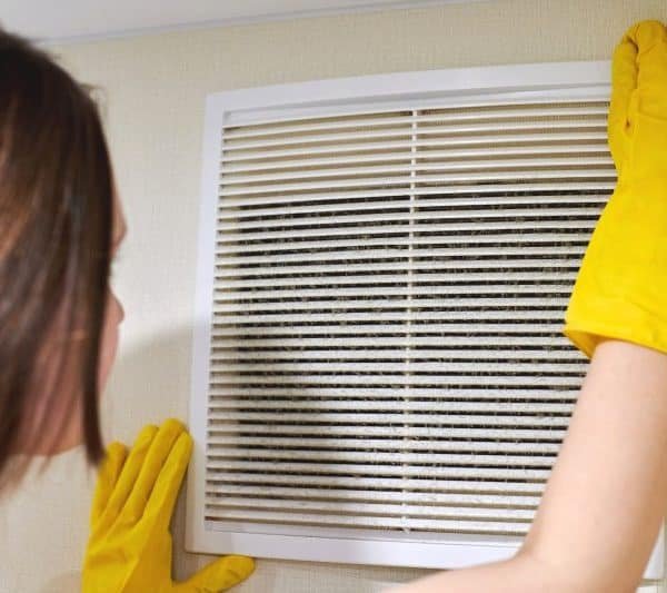 Holding ventilation grill of HVAC for cleaning or replacing.
