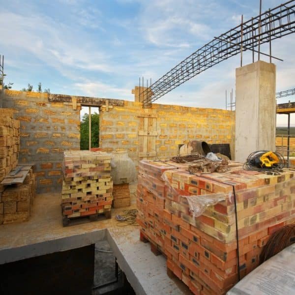 Une maison en construction avec des briques au sol.