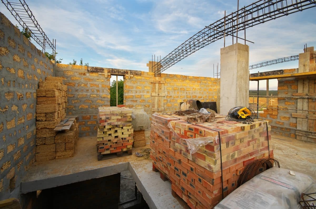 Une maison en construction avec des briques au sol.