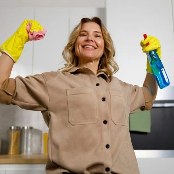 Une femme nettoyant une cuisine avec une paire de gants.