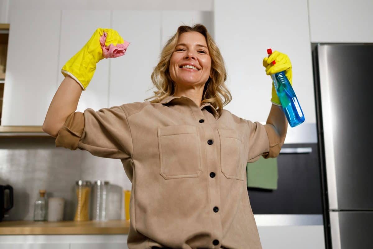 Une femme nettoyant une cuisine avec une paire de gants.