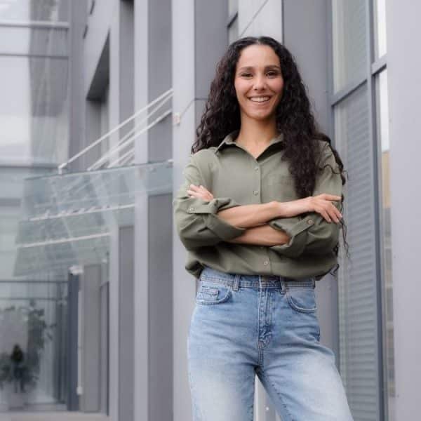 In city downtown background standing single smiling happy proud 30s woman in casual blouse strong