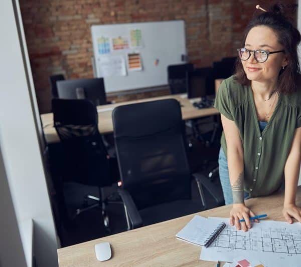 Interior designer or architect in casual wear with messy hairdo smiling aside while working on a