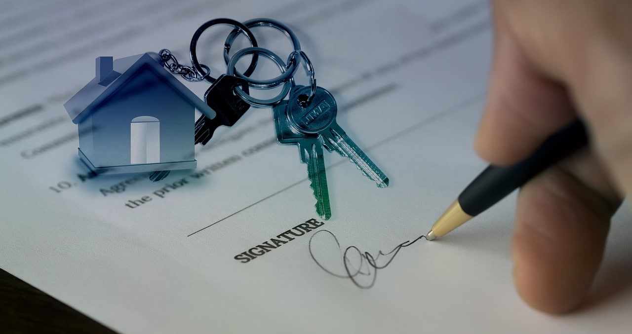 Une personne signant un document avec des clés et une maison dessus.