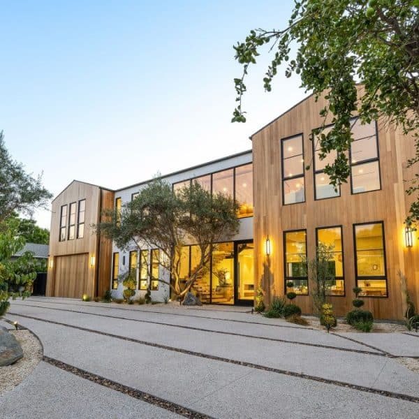 Modern wooden house with large windows and trees.