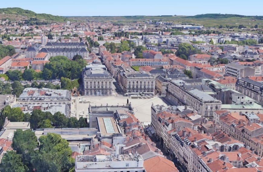 Vue aérienne d'un paysage urbain européen avec des bâtiments aux toits rouges, une place centrale et de la verdure environnante.