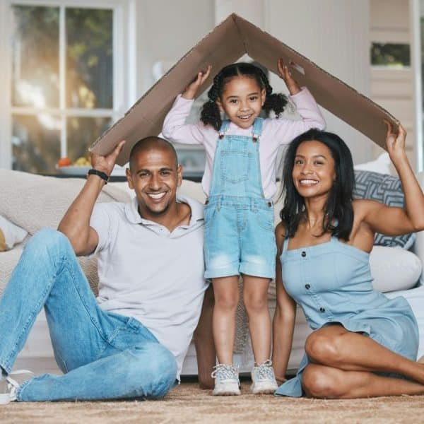 Portrait, toit en carton et famille dans le salon, assurance habitation et soins avec protection, sourire a