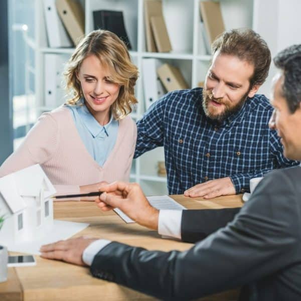 portrait of couple having meeting with realtor in real estate agency office
