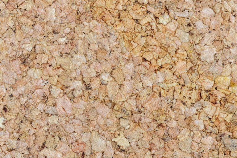 Gros plan d'une surface de panneau de liège, montrant sa texture naturelle et irrégulière et ses tons bruns terreux.