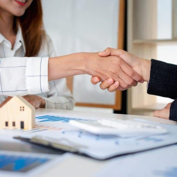 Real estate agents shakehands to congratulate clients on accepting the offer to buy a home at a spec