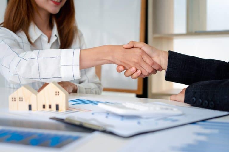 Real estate agents shakehands to congratulate clients on accepting the offer to buy a home at a spec