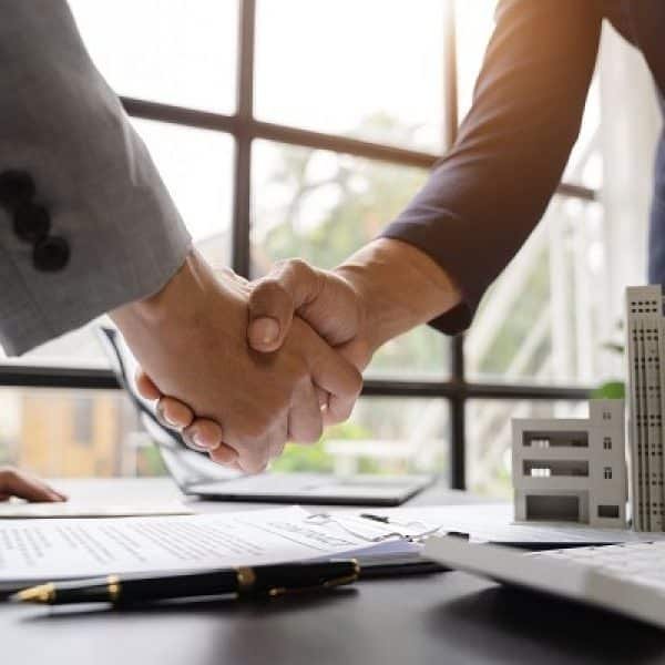 Deux hommes d’affaires se serrant la main devant un bureau.