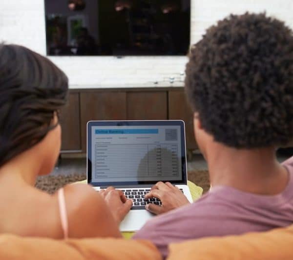 Rear View Of Couple Using Online Banking On Laptop