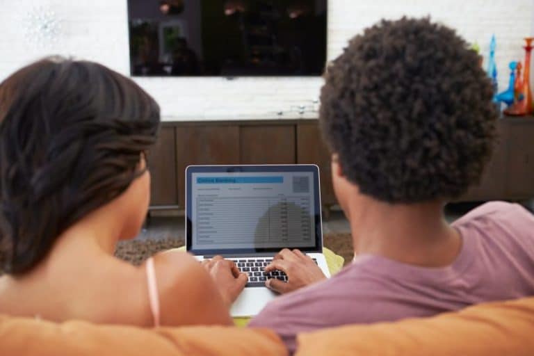 Rear View Of Couple Using Online Banking On Laptop