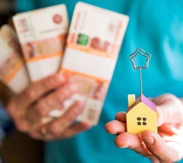 Rising house prices. Man is holding money in his hand and house.real estate or property investment