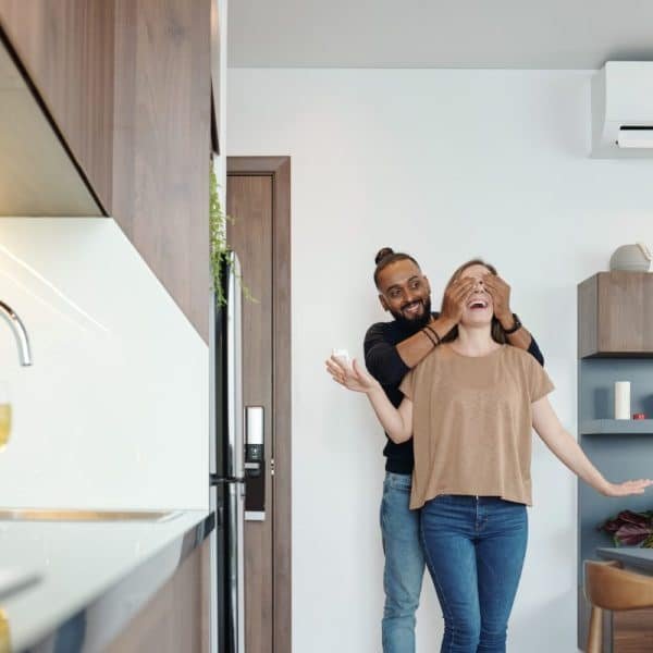 Un homme et une femme debout devant un climatiseur dans une cuisine.