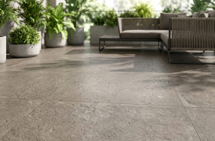 Terrasse moderne avec des carreaux effet pierre mouillés et un canapé d'extérieur entouré de plantes en pot.