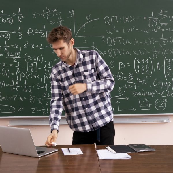 the adult student sitting at the table and working laptop, doing homework research