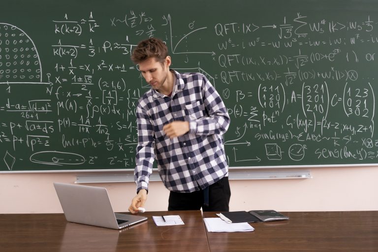 the adult student sitting at the table and working laptop, doing homework research