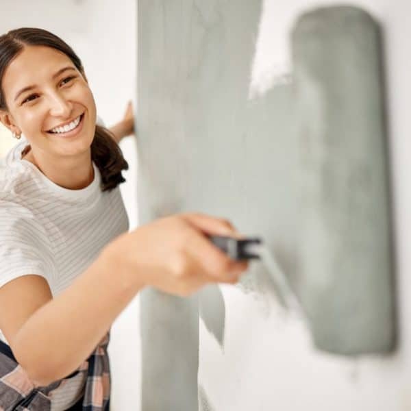 Theres nothing you cant do yourself. Shot of a beautiful young woman painting a wall at home.