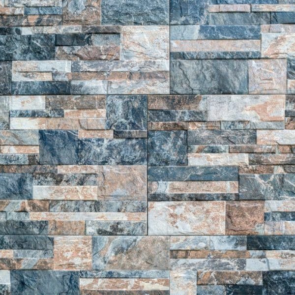 Un mur détaillé composé de dalles de pierre rectangulaires imbriquées dans différentes nuances de gris et de marron.