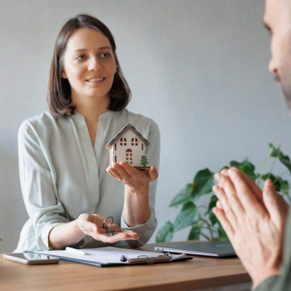woman realtor or mortgage consultant holds a miniature model of a house and the keys to an apartment