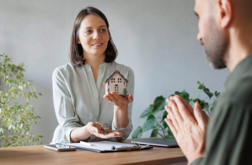 woman realtor or mortgage consultant holds a miniature model of a house and the keys to an apartment