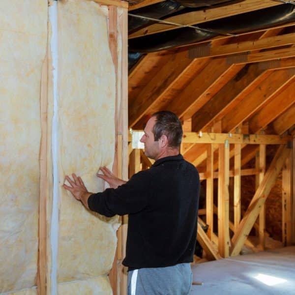 Homme installant une isolation dans un grenier à ossature bois.