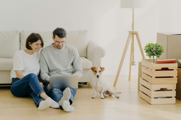 Jeune couple européen rénovant sa maison, concentré sur son ordinateur portable.