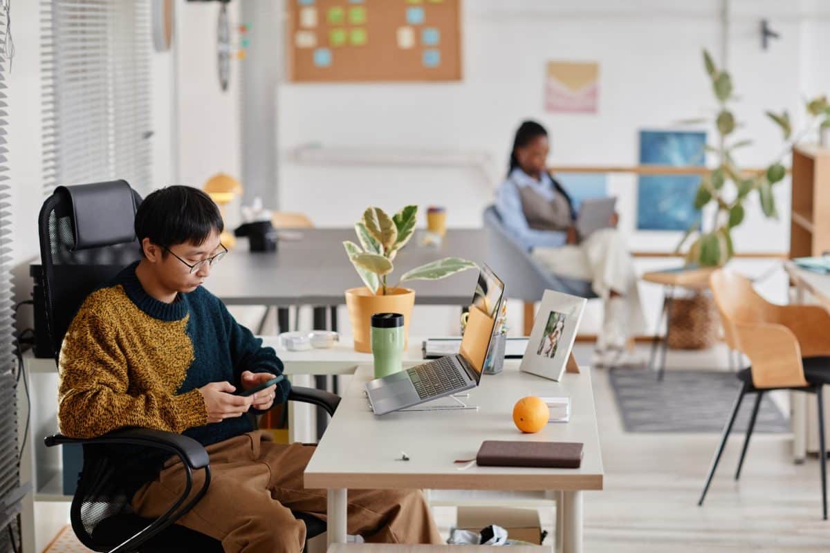 Young Professional Using Smartphone in Modern Office Setting